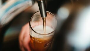 person filling clear glass with liquid